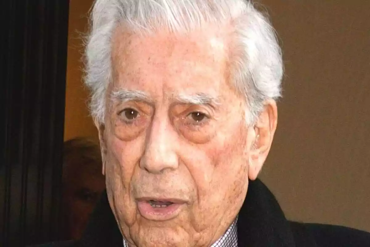 Primer pla de Mario Vargas Llosa amb el rostre seriós mentre surt al carrer des d'un edifici