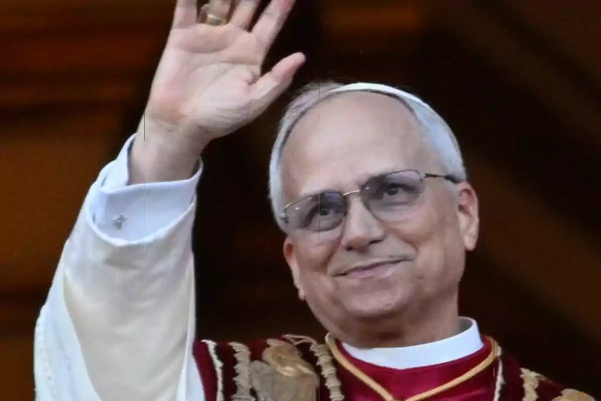 Primer pla del Papa Lleó XIV amb ulleres i vestimenta religiosa aixeca la mà en senyal de salutació. Primer pla del Papa Lleó XIV amb ulleres i vestimenta religiosa aixeca la mà en senyal de salutació.