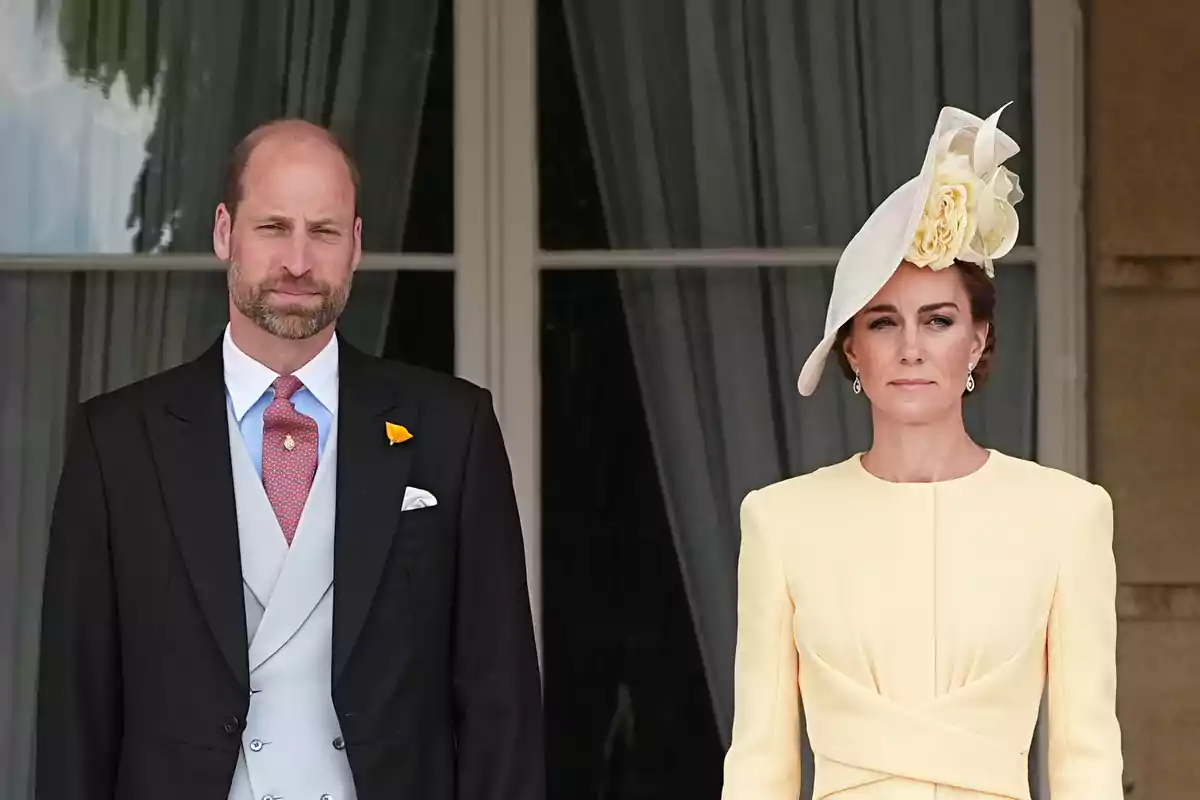 El príncep Guillem i Kate Middleton elegantment vestida de peu davant d'una finestra amb cortines. El príncep Guillem i Kate Middleton elegantment vestida de peu davant d'una finestra amb cortines.