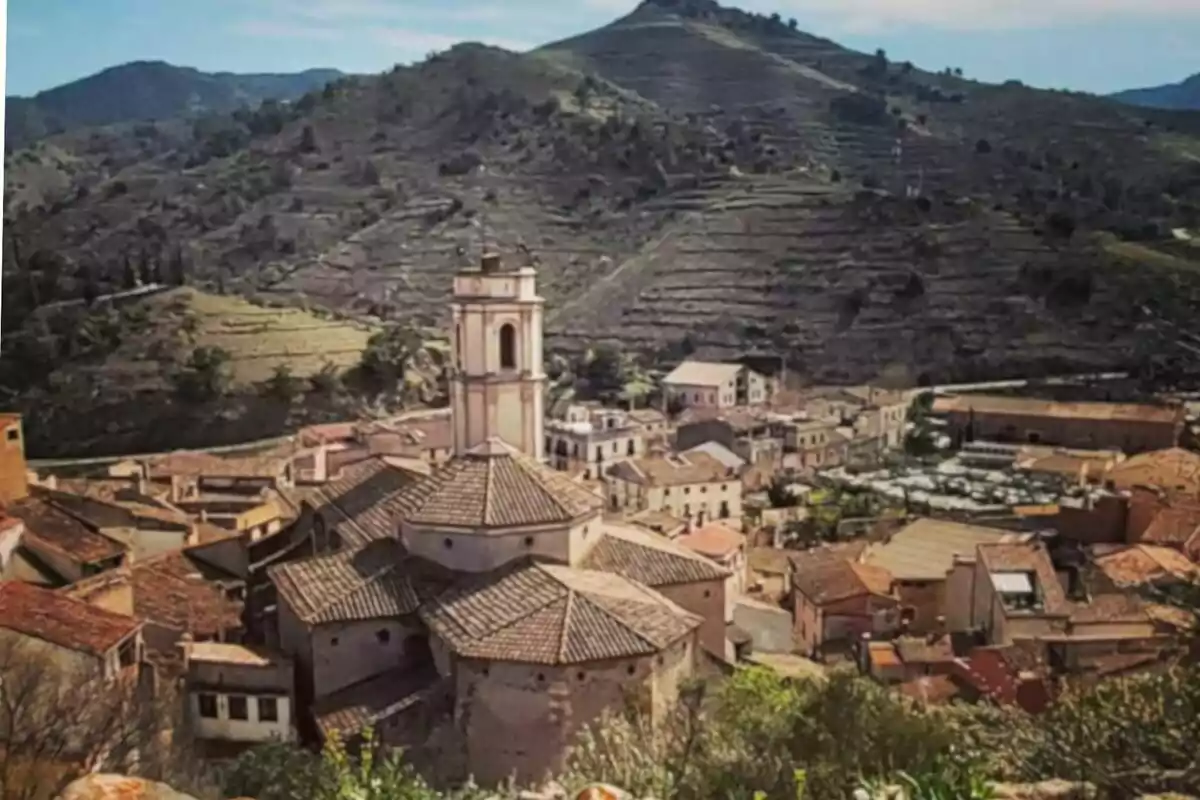 Vista panorámica de un pueblo con una iglesia en el centro y montañas al fondo.