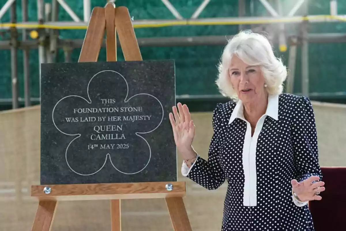 La reina Camila dempeus al costat d'una placa commemorativa en un esdeveniment de col·locació de la primera pedra. La reina Camila dempeus al costat d'una placa commemorativa en un esdeveniment de col·locació de la primera pedra.