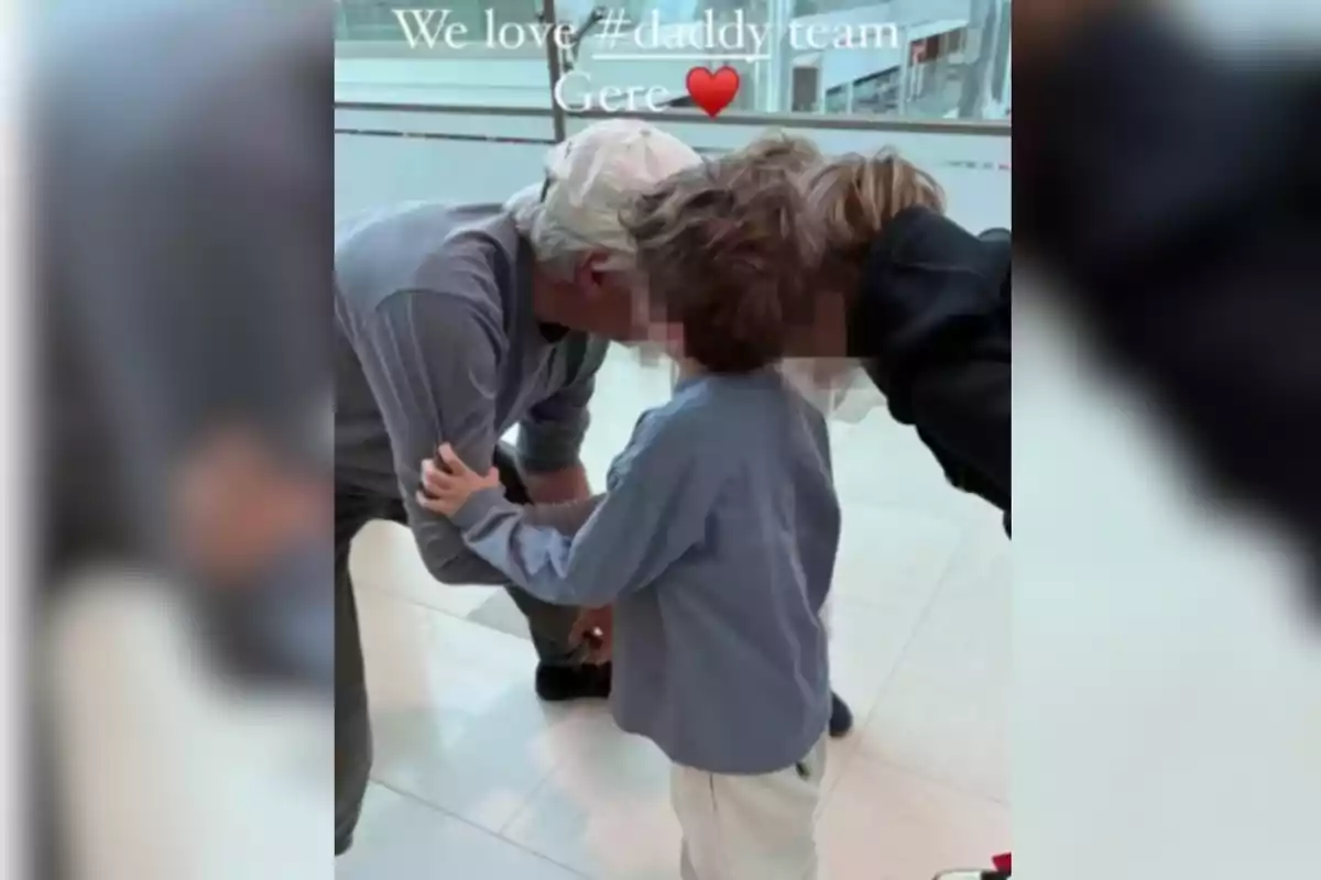 Un home amb gorra blanca s'inclina per abraçar un nen en un espai interior il·luminat. Un home amb gorra blanca s'inclina per abraçar un nen en un espai interior il·luminat.