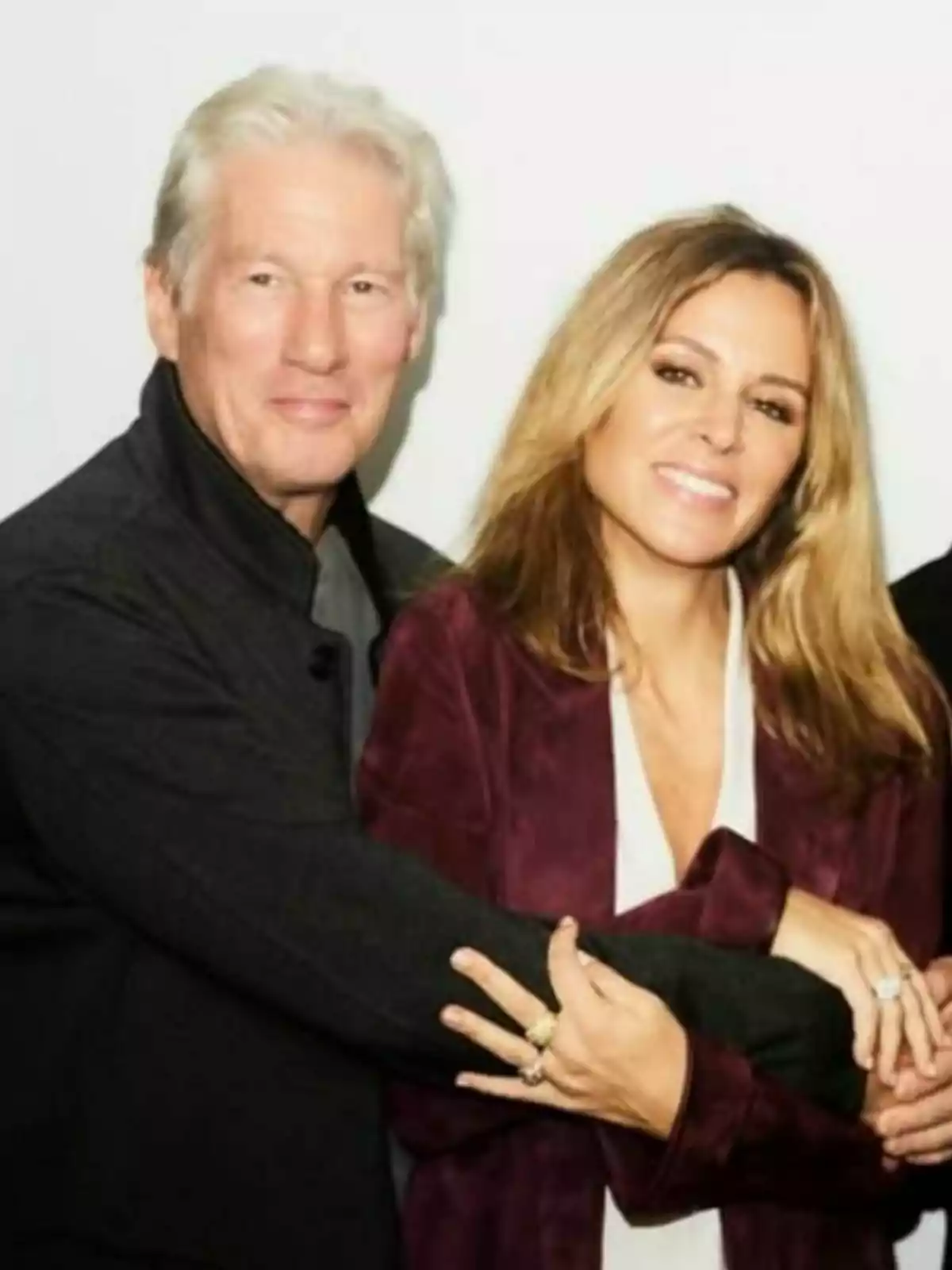 Couple—Alejandra Silva and Richard Gere—embracing and smiling in front of a white wall. Couple—Alejandra Silva and Richard Gere—embracing and smiling in front of a white wall.