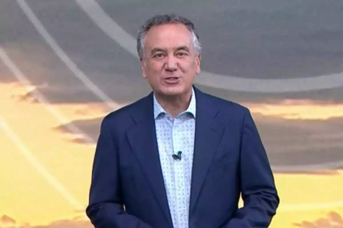 Pla mig de Roberto Brasero dret amb vestit fosc i camisa clara davant d'un fons amb tons càlids. Pla mig de Roberto Brasero dret amb vestit fosc i camisa clara davant d'un fons amb tons càlids.