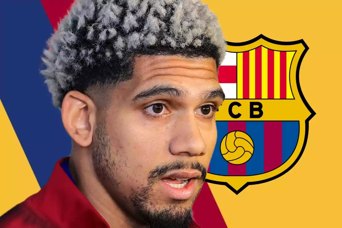 Un jugador de futbol amb cabell arrissat i barba davant d'un escut d'un equip de futbol.