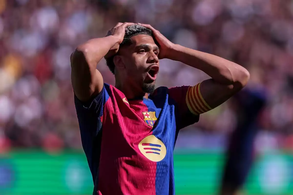 A player in a blue and red uniform puts his hands on his head in a gesture of surprise or frustration during a match.