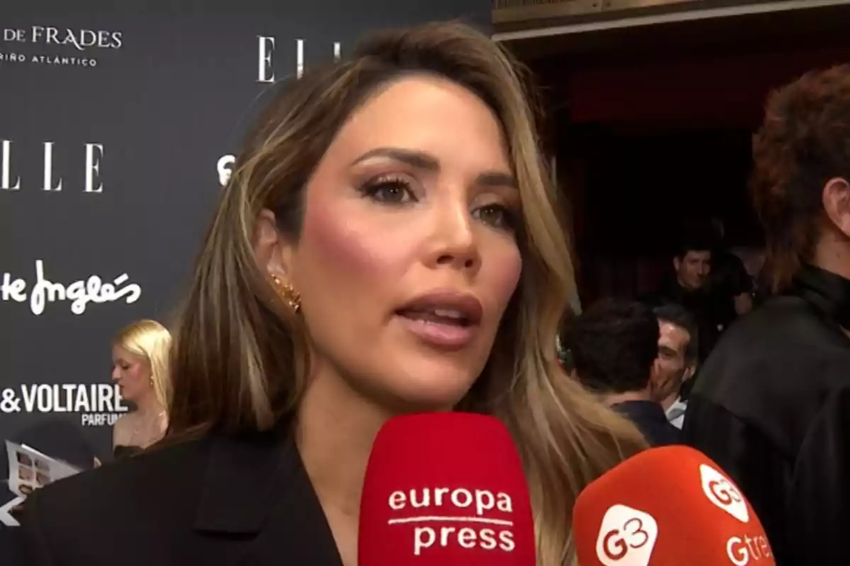 Rosanna Zanetti sent entrevistada en un esdeveniment amb un fons de logotips i micròfons vermells davant seu Rosanna Zanetti sent entrevistada en un esdeveniment amb un fons de logotips i micròfons vermells davant seu