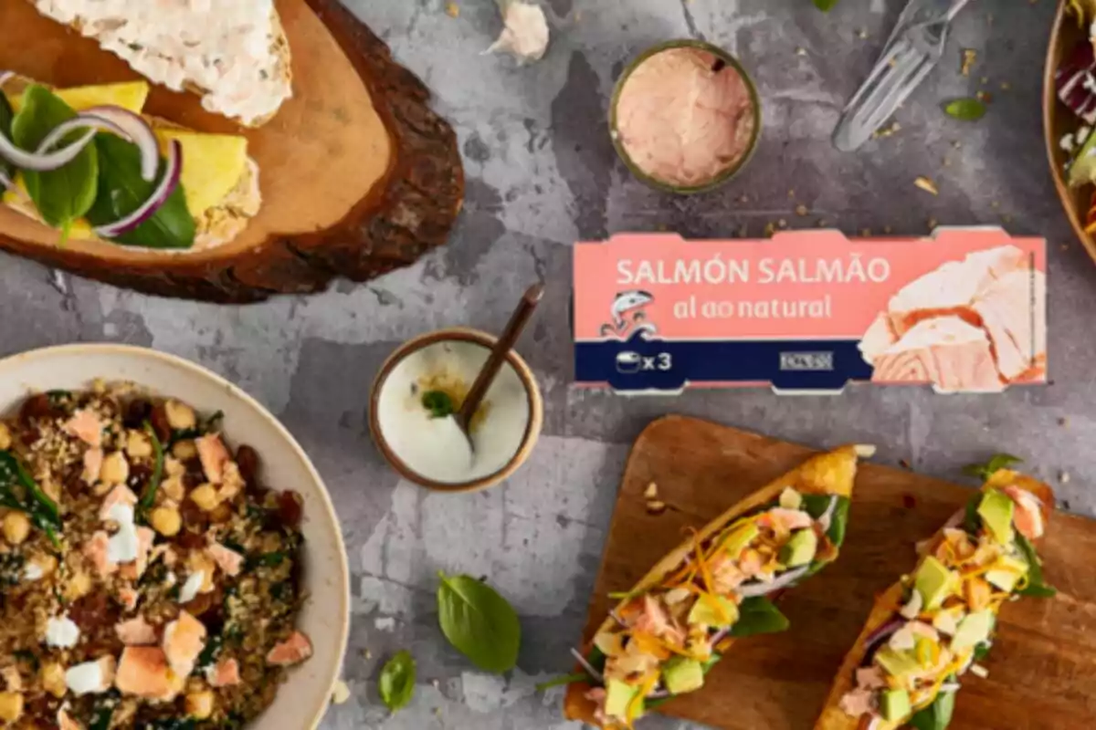 Una varietat de plats gurmet amb salmó al natural de Mercadona al centre; incloent amanides, torrades i un dip, presentats sobre una taula de pedra. Una varietat de plats gurmet amb salmó al natural de Mercadona al centre; incloent amanides, torrades i un dip, presentats sobre una taula de pedra.