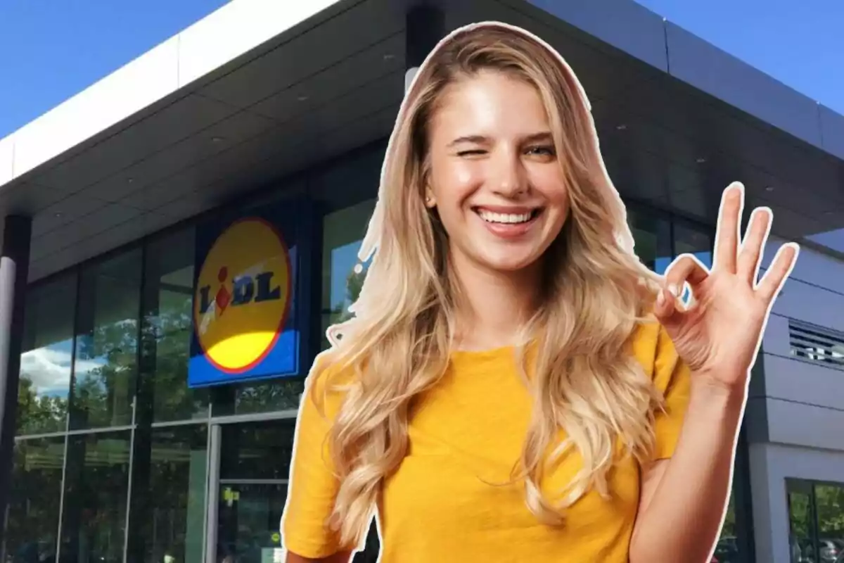 Una persona somrient amb samarreta groga fa un gest de "ok" davant d'un supermercat Lidl.