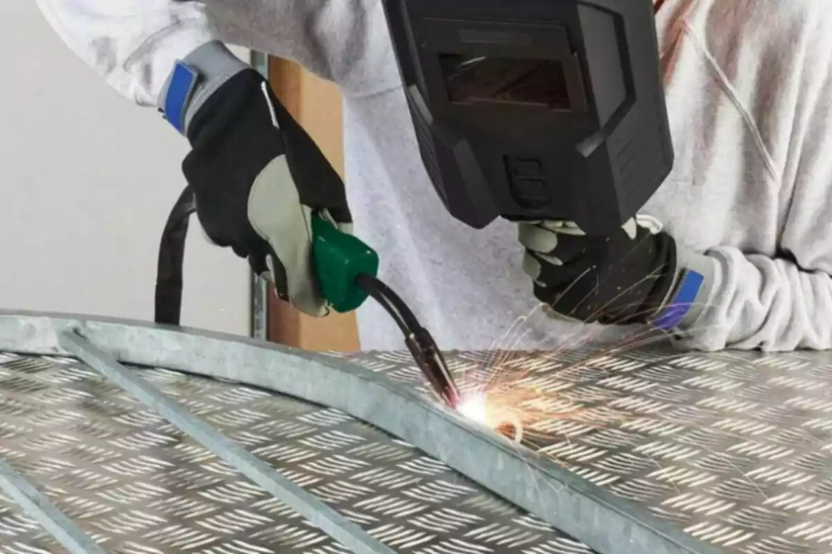 Persona soldant una estructura metàl·lica amb equip de protecció. Persona soldant una estructura metàl·lica amb equip de protecció.