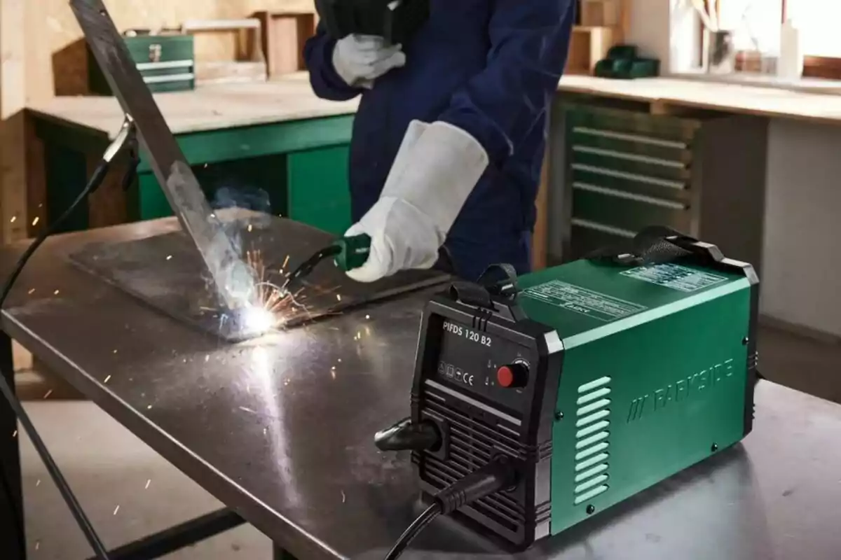 Persona soldant una peça de metall en un taller amb un equip de soldadura verd sobre una taula. Persona soldant una peça de metall en un taller amb un equip de soldadura verd sobre una taula.
