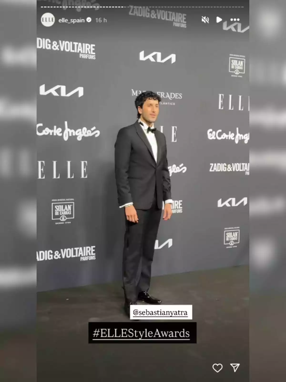 Sebastián Yatra con esmoquin negro posando en la alfombra de los ELLE Style Awards frente a un fondo con logotipos de marcas y patrocinadores. Sebastián Yatra con esmoquin negro posando en la alfombra de los ELLE Style Awards frente a un fondo con logotipos de marcas y patrocinadores.