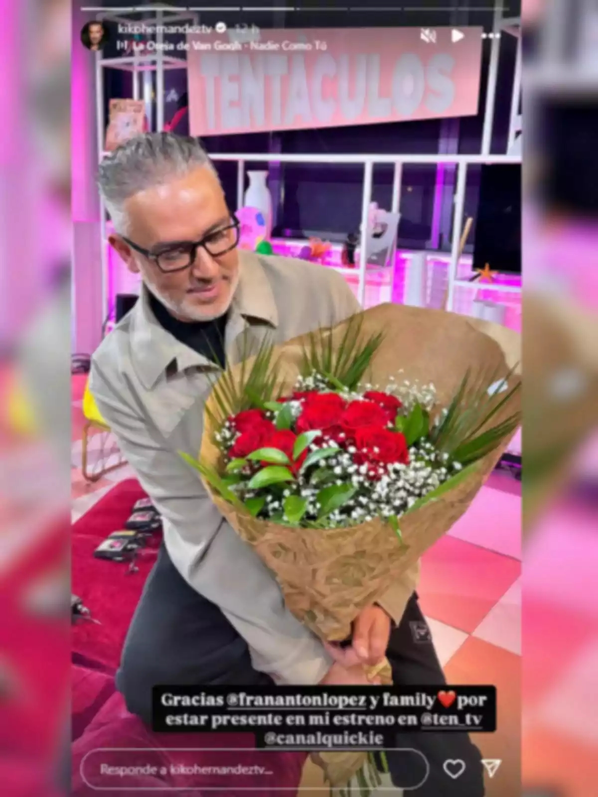 Kiko Hernández sosté un ram de flors en un entorn acolorit amb llums de neó i un cartell que diu Kiko Hernández sosté un ram de flors en un entorn acolorit amb llums de neó i un cartell que diu