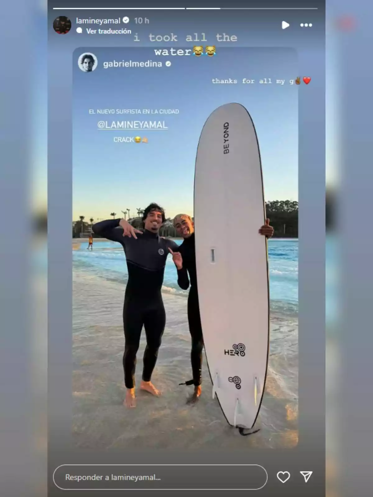 Lamine Yamal i un altre home amb vestits de neoprè posen somrients al costat d’una taula de surf a la vora d’una piscina d’onades Lamine Yamal i un altre home amb vestits de neoprè posen somrients al costat d’una taula de surf a la vora d’una piscina d’onades