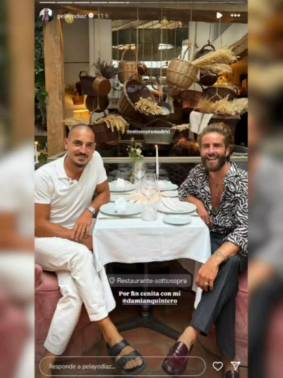 Damián Quintero i Pelayo Díaz asseguts en una taula d’un restaurant elegantment decorat, amb cistelles i plantes penjants de fons, tots dos somriuen i semblen gaudir d’un sopar junts. Damián Quintero i Pelayo Díaz asseguts en una taula d’un restaurant elegantment decorat, amb cistelles i plantes penjants de fons, tots dos somriuen i semblen gaudir d’un sopar junts.
