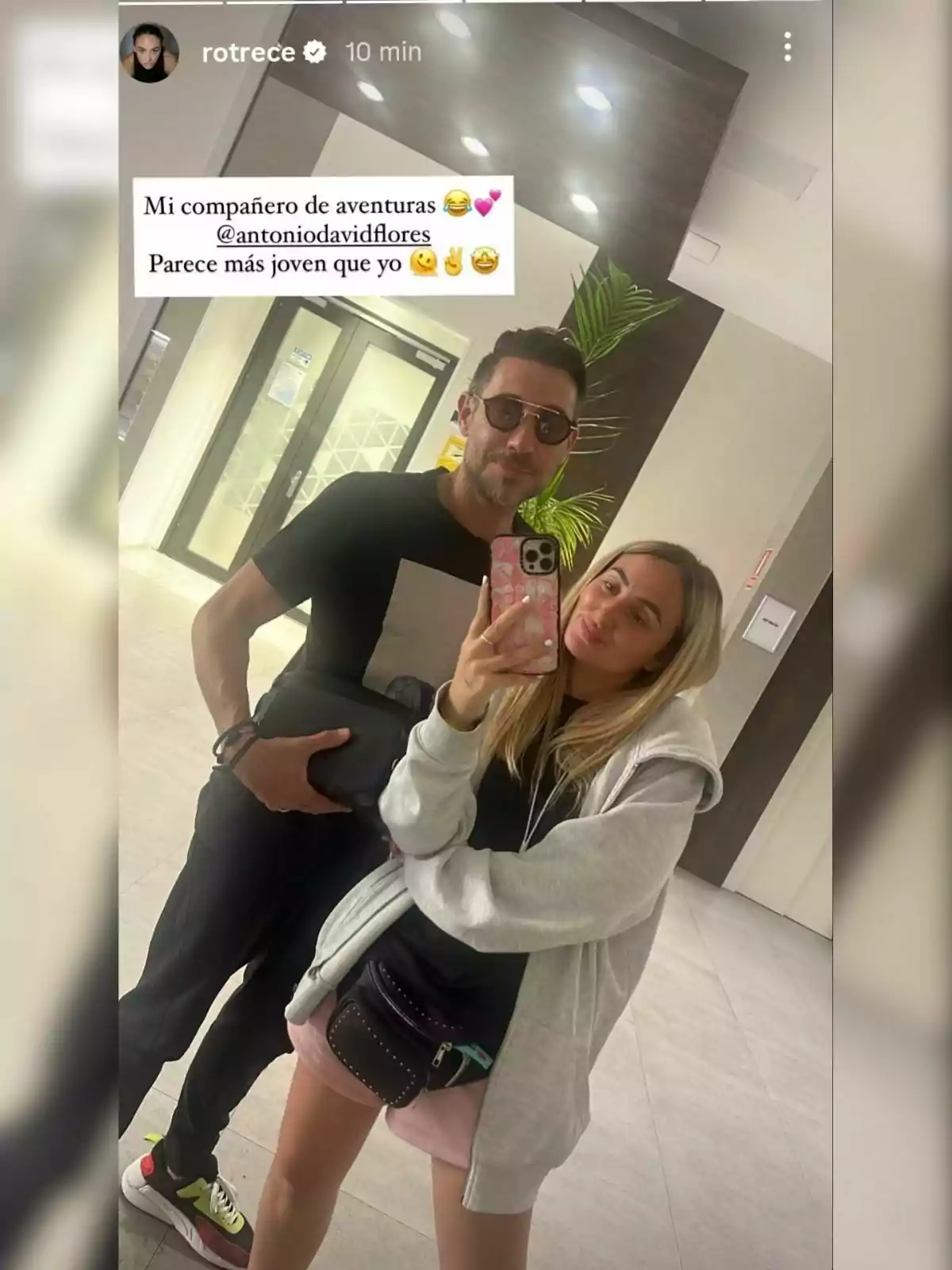 Antonio David i Rocío Flores posen juntes per a una selfie en un vestíbul modern, una d'elles sosté el telèfon mentre ambdues somriuen i vesteixen roba casual. Antonio David i Rocío Flores posen juntes per a una selfie en un vestíbul modern, una d'elles sosté el telèfon mentre ambdues somriuen i vesteixen roba casual.