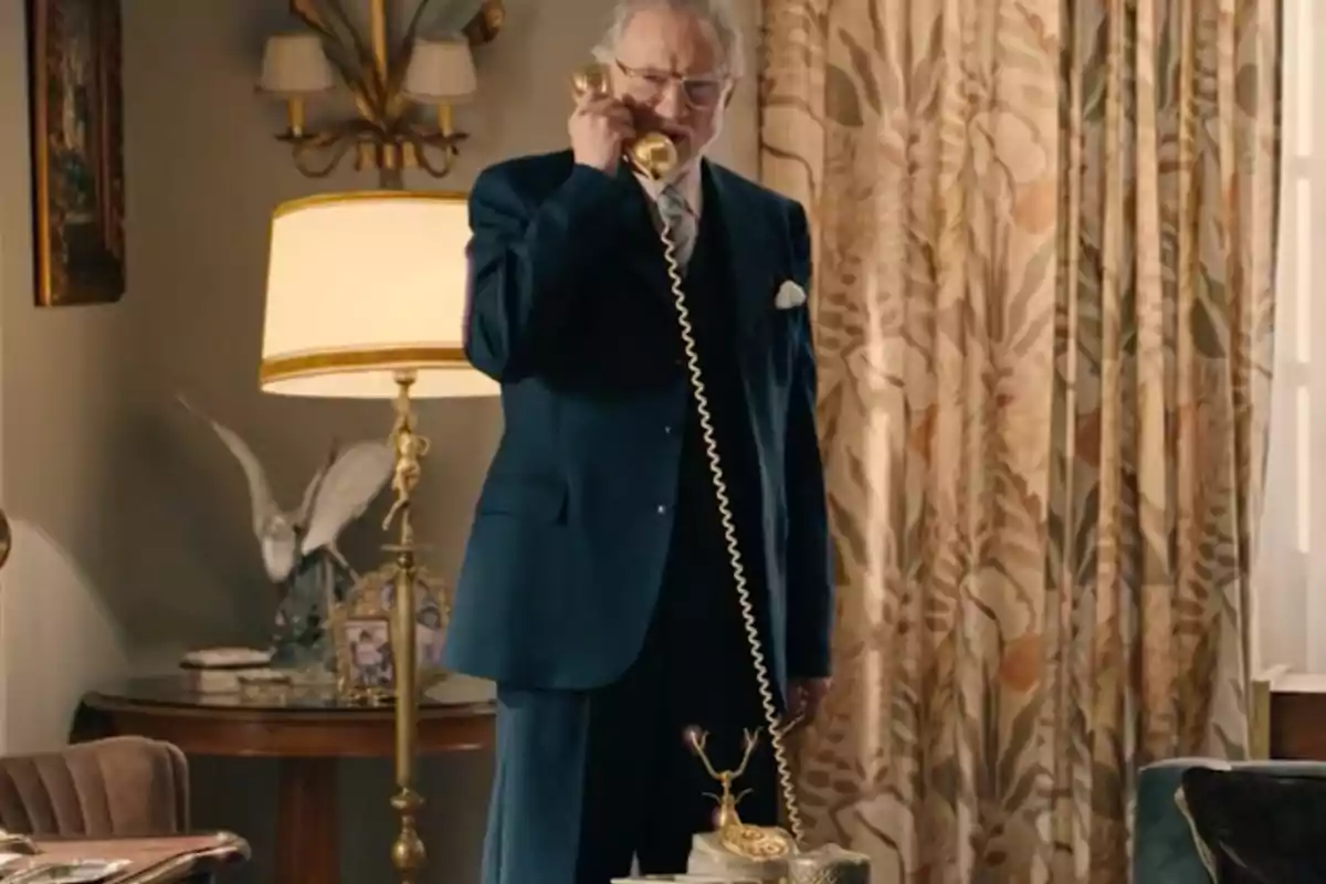 Damián dret en una sala elegant parlant per un telèfon antic daurat. Captura de 'Sueños de libertad' Damián dret en una sala elegant parlant per un telèfon antic daurat. Captura de 'Sueños de libertad'