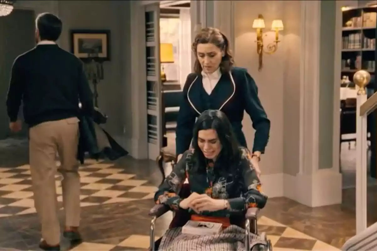 Manuela empeny una cadira de rodes en què la María està asseguda i plorant mentre un home s’allunya caminant en una sala elegant. Captura de 'Sueños de libertad' Manuela empeny una cadira de rodes en què la María està asseguda i plorant mentre un home s’allunya caminant en una sala elegant. Captura de 'Sueños de libertad'