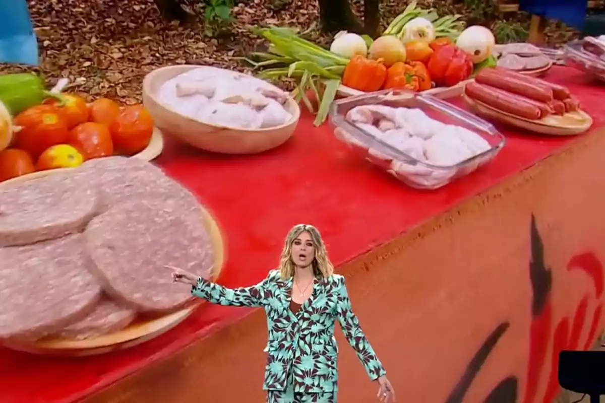 Sandra Barneda amb un vestit estampat està dreta davant d'una taula plena d'aliments com verdures, embotits i carn crua. Captura de 'Supervivientes'. Sandra Barneda amb un vestit estampat està dreta davant d'una taula plena d'aliments com verdures, embotits i carn crua. Captura de 'Supervivientes'.