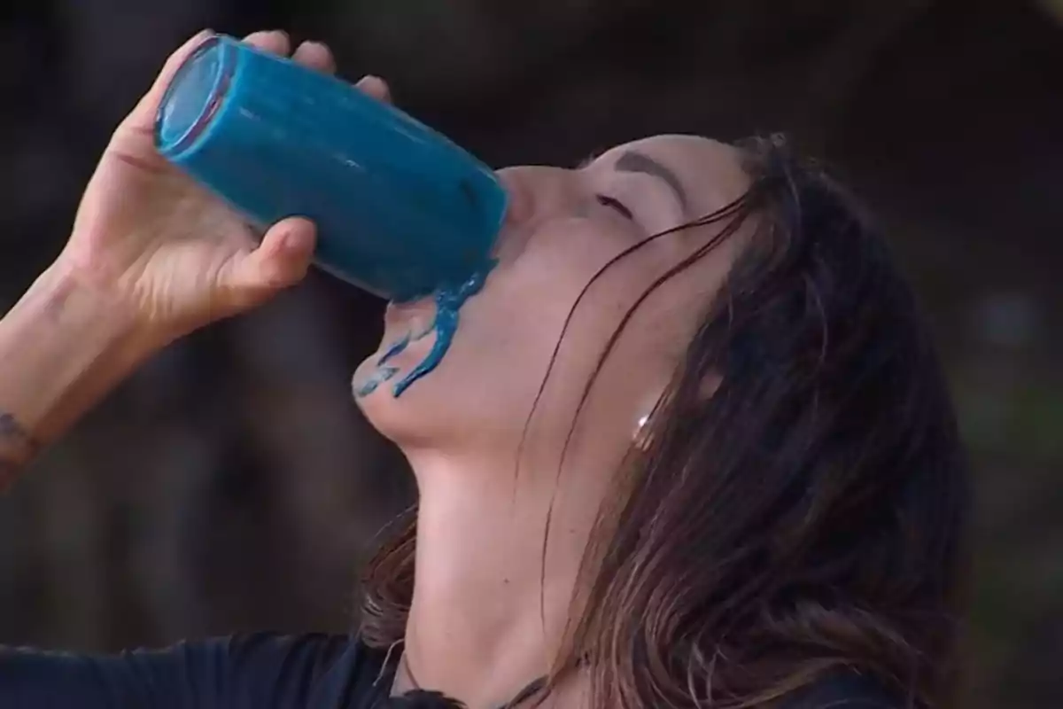 Anita beu d'un got que conté un líquid blau, mentre part del líquid li regalima per la cara. Captura de 'Supervivientes'. Anita beu d'un got que conté un líquid blau, mentre part del líquid li regalima per la cara. Captura de 'Supervivientes'.