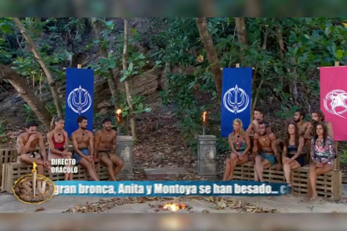 Un grup de persones assegudes en un entorn selvàtic, amb torxes enceses i banderes de colors darrere d'ells, mentre un text a la part inferior menciona un esdeveniment recent. Captura de 'Supervivientes'. Un grup de persones assegudes en un entorn selvàtic, amb torxes enceses i banderes de colors darrere d'ells, mentre un text a la part inferior menciona un esdeveniment recent. Captura de 'Supervivientes'.