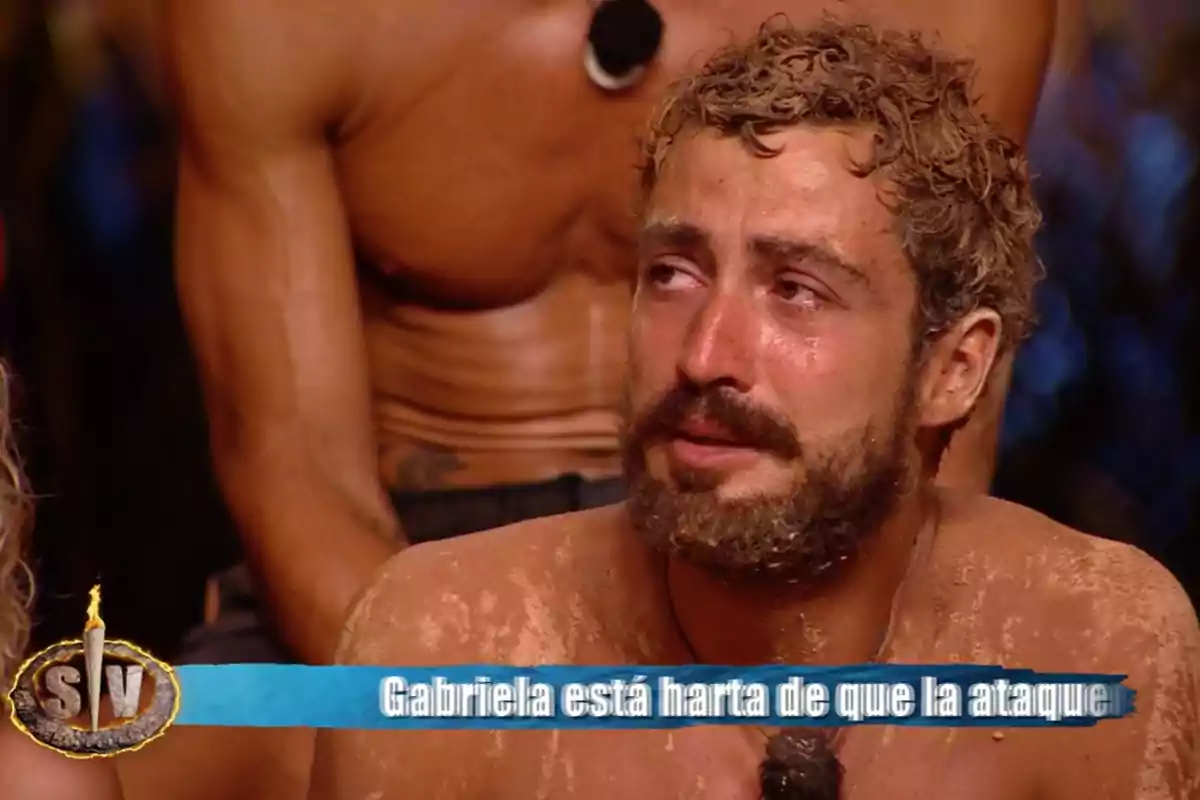 Joshua Velázquez està plorant mentre està cobert de sorra, amb un micròfon al pit i una persona musculosa darrere d'ell. Captura de 'Supervivientes'. Joshua Velázquez està plorant mentre està cobert de sorra, amb un micròfon al pit i una persona musculosa darrere d'ell. Captura de 'Supervivientes'.
