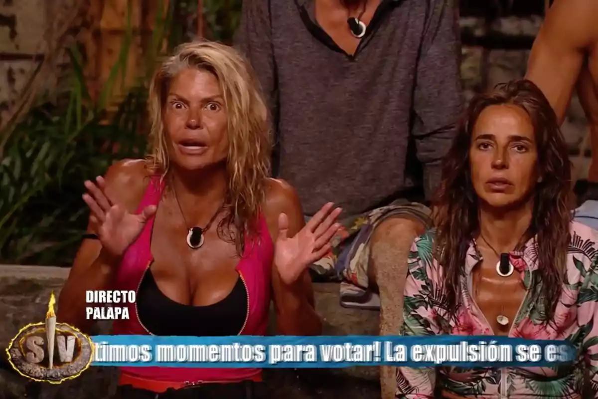 Makoke i Carmen Alcayde amb expressió seriosa i sorpresa assegudes en un plató de televisió d’un reality show de supervivència amb un rètol blau a la part inferior de la imatge. Captura de ‘Supervivientes’ Makoke i Carmen Alcayde amb expressió seriosa i sorpresa assegudes en un plató de televisió d’un reality show de supervivència amb un rètol blau a la part inferior de la imatge. Captura de ‘Supervivientes’