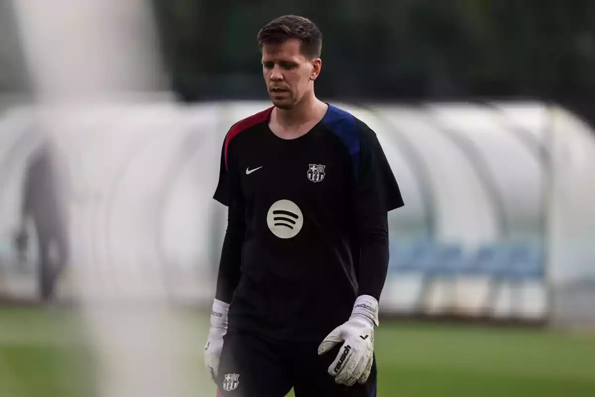 Un jugador de futbol amb uniforme negre i guants blancs a un camp d'entrenament. Un jugador de futbol amb uniforme negre i guants blancs a un camp d'entrenament.