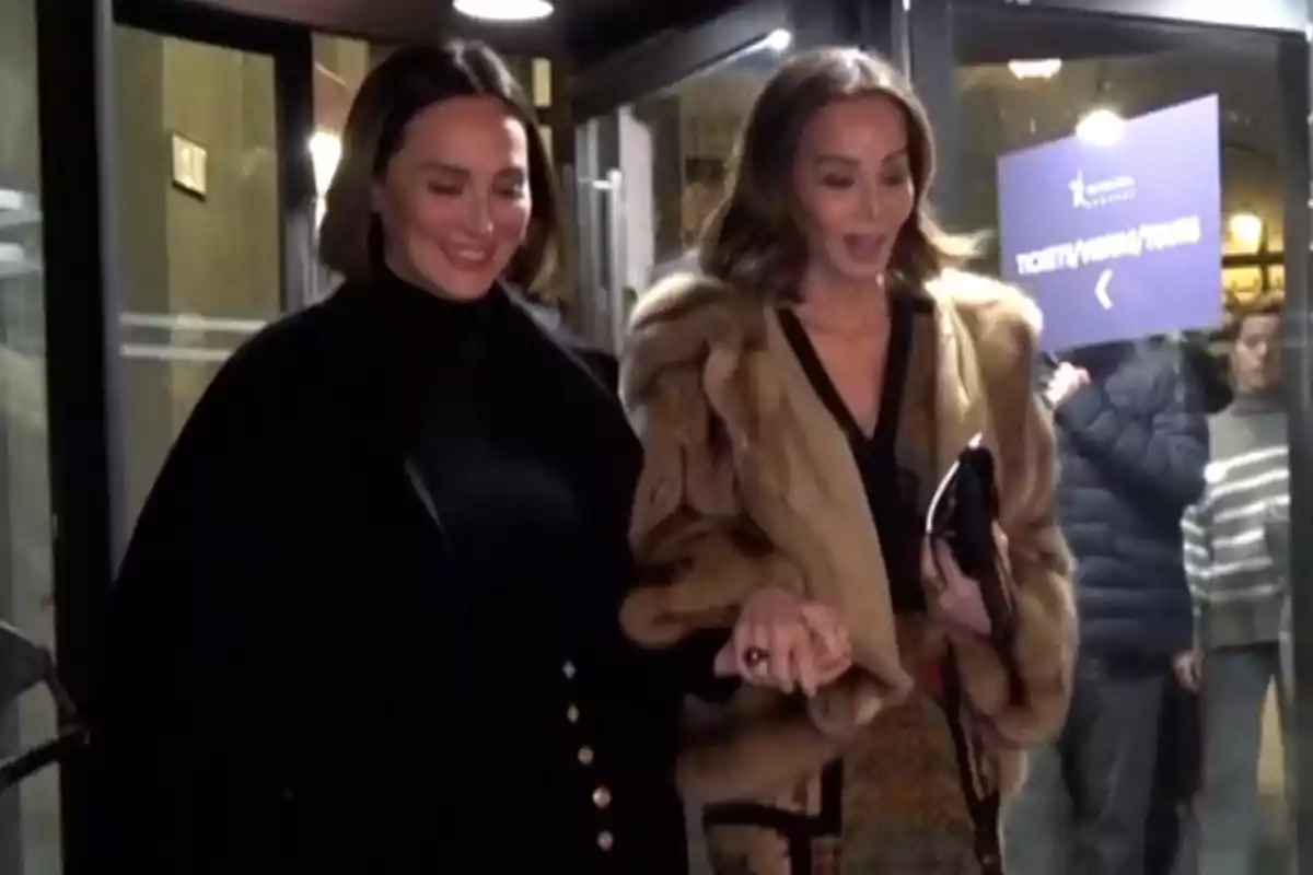 Tamara Falcó i Isabel Preysler somrients sortint d'un edifici, una d'elles porta un abric de pell i l'altra un abric fosc. Tamara Falcó i Isabel Preysler somrients sortint d'un edifici, una d'elles porta un abric de pell i l'altra un abric fosc.