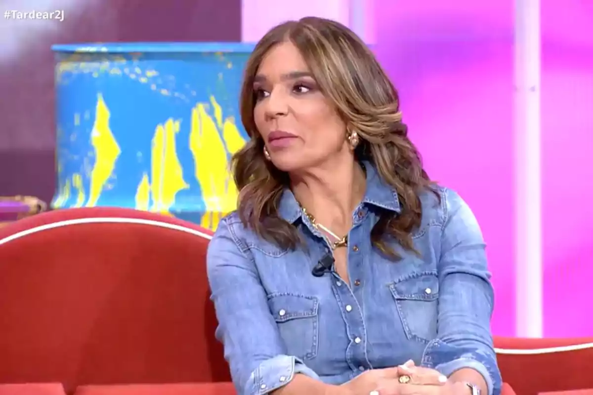 Raquel Bollo asseguda en un sofà vermell amb camisa texana en un plató de televisió amb fons acolorit. Captura de 'TardeAR' Raquel Bollo asseguda en un sofà vermell amb camisa texana en un plató de televisió amb fons acolorit. Captura de 'TardeAR'