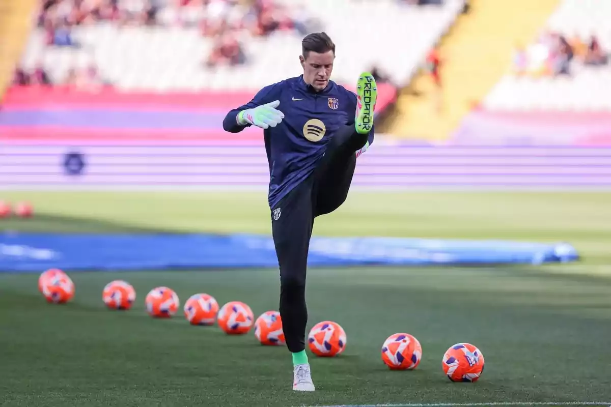 A player performs warm-up exercises on the field with several orange balls around. A player performs warm-up exercises on the field with several orange balls around.