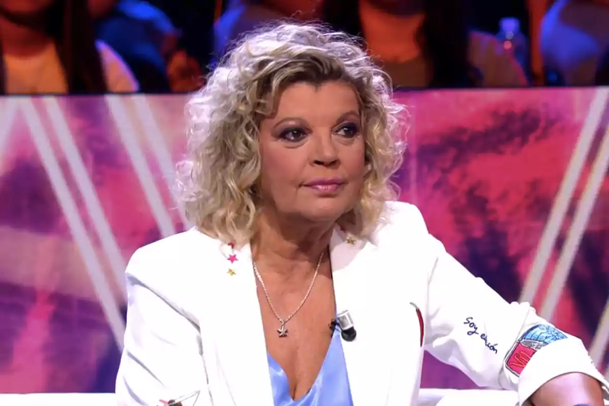 Terelu Campos amb jaqueta blanca asseguda en un plató de televisió amb fons acolorit Terelu Campos amb jaqueta blanca asseguda en un plató de televisió amb fons acolorit