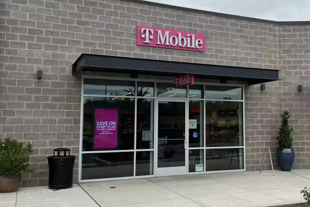A mobile phone store with a pink sign above the entrance and a promotional poster in the window. A mobile phone store with a pink sign above the entrance and a promotional poster in the window.