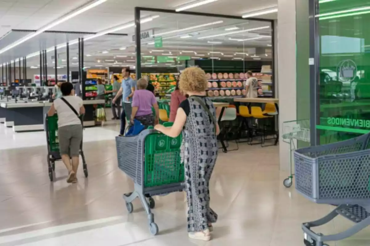 Personas empujando carritos de compras en el interior de un supermercado.