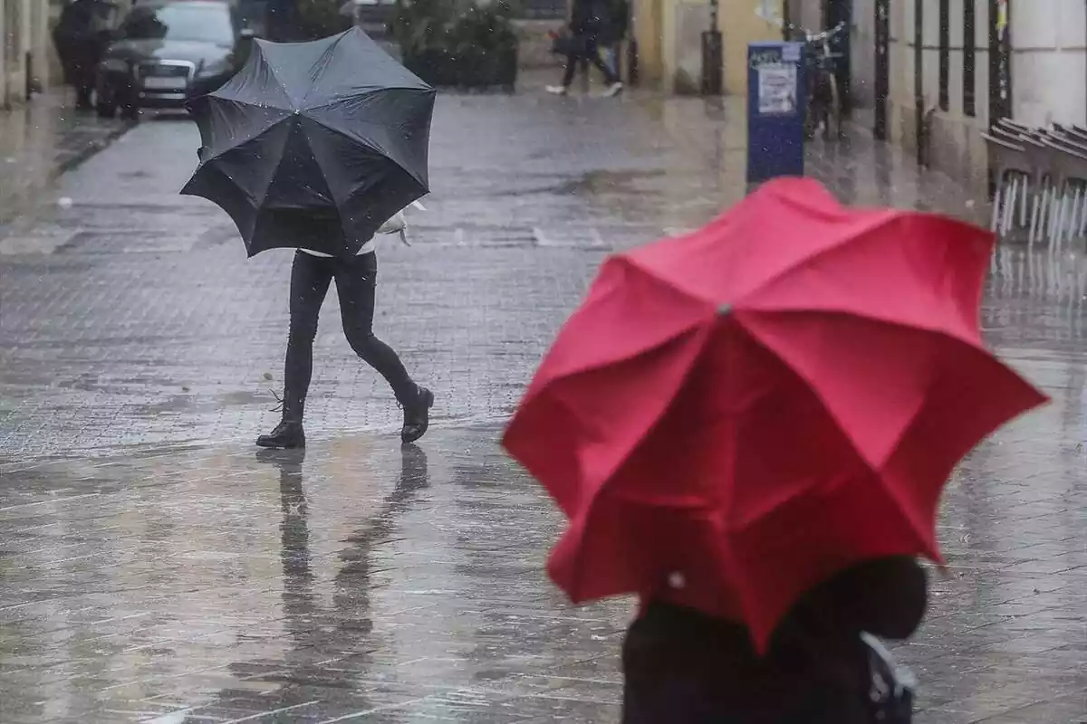 Dues persones amb paraigües enmig del carrer durant una tempesta