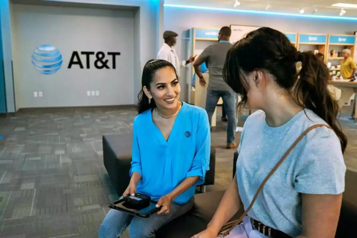 Dues persones conversen en una botiga d'AT&T, una d'elles porta un uniforme blau i sosté una tauleta. Dues persones conversen en una botiga d'AT&T, una d'elles porta un uniforme blau i sosté una tauleta.