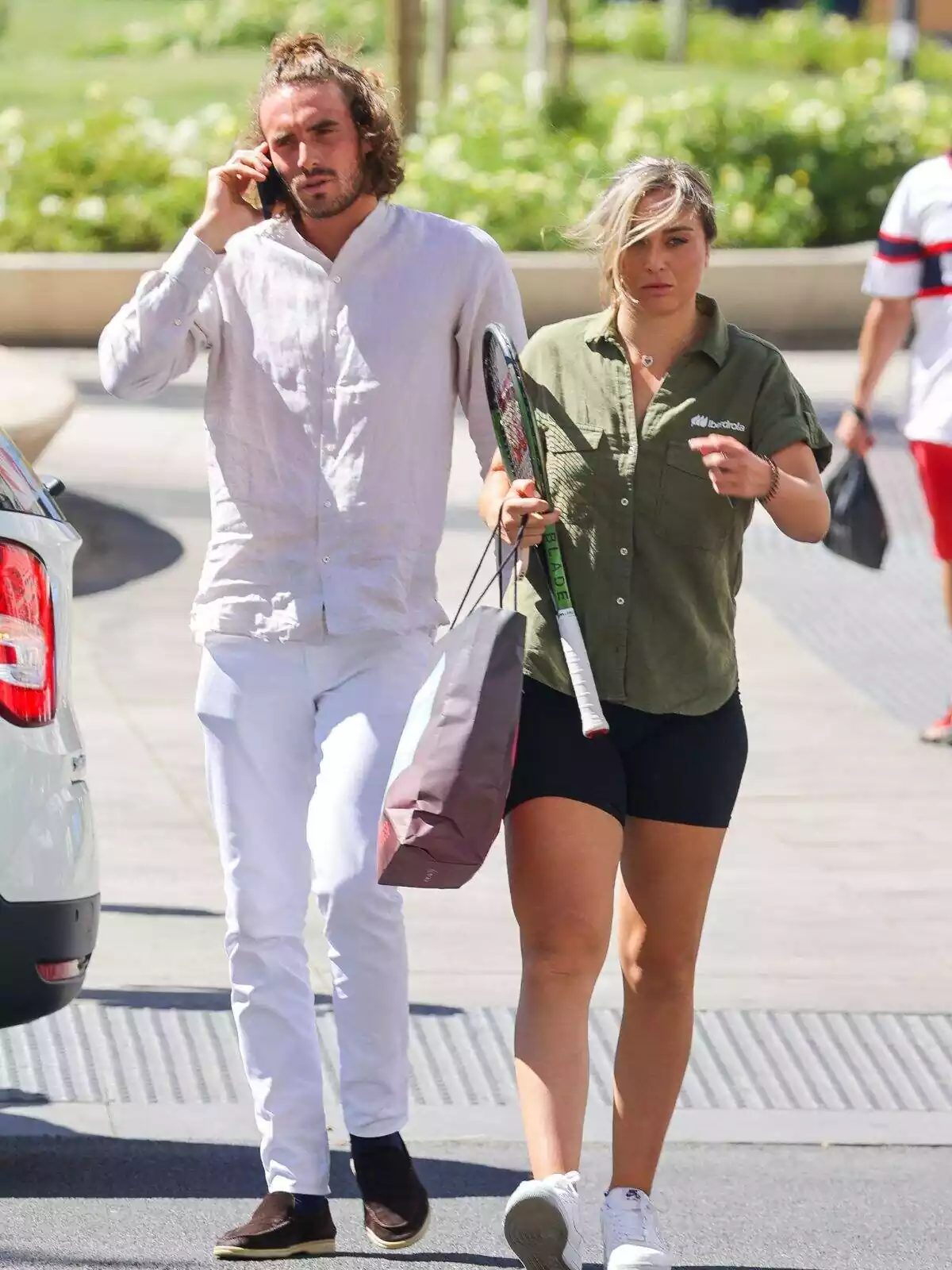 Tsisipás with his cell phone to his ear and Paula Badosa serious with her hair on her face Tsisipás with his cell phone to his ear and Paula Badosa serious with her hair on her face