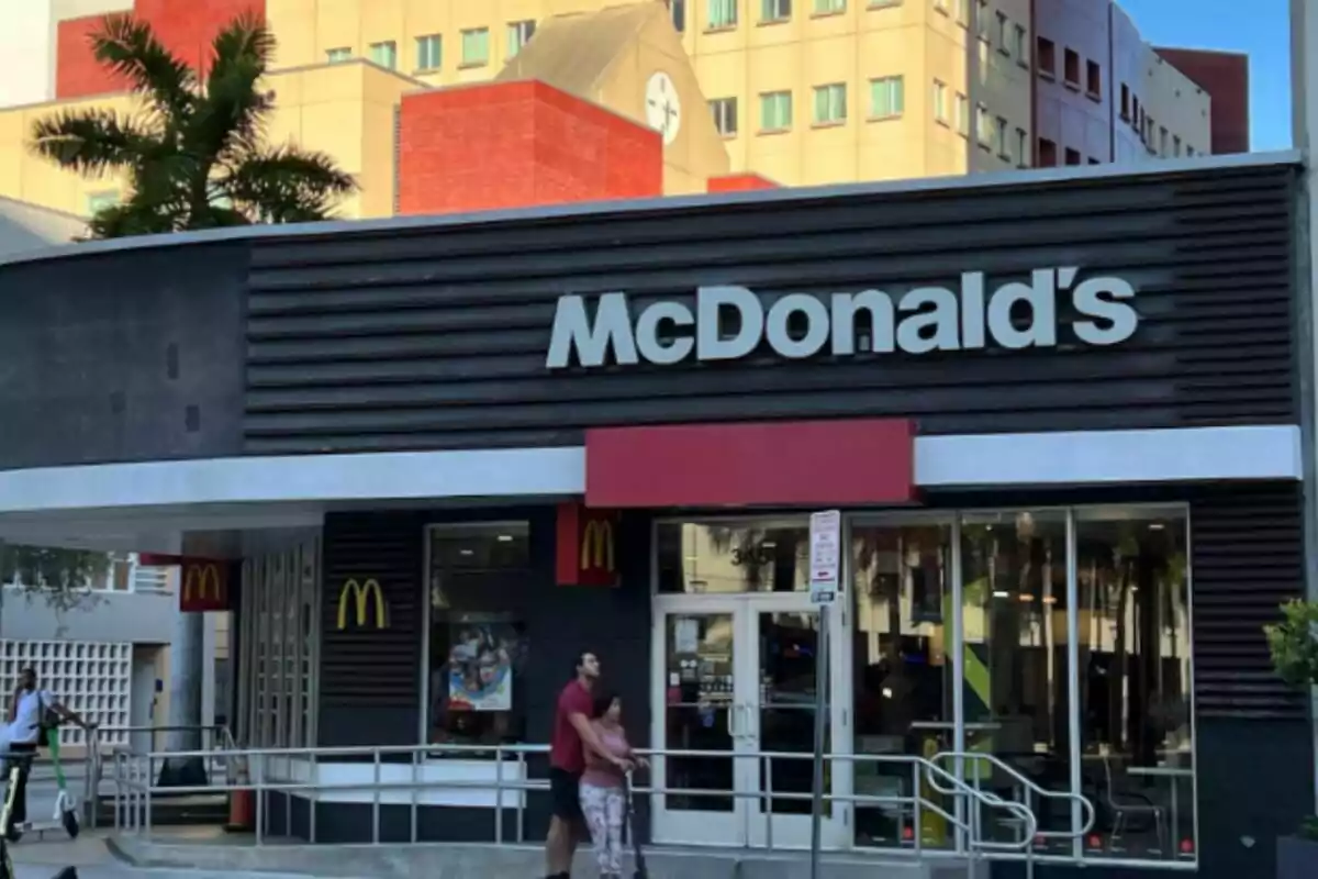In front of a McDonald's restaurant with people on electric scooters and a building in the background. In front of a McDonald's restaurant with people on electric scooters and a building in the background.