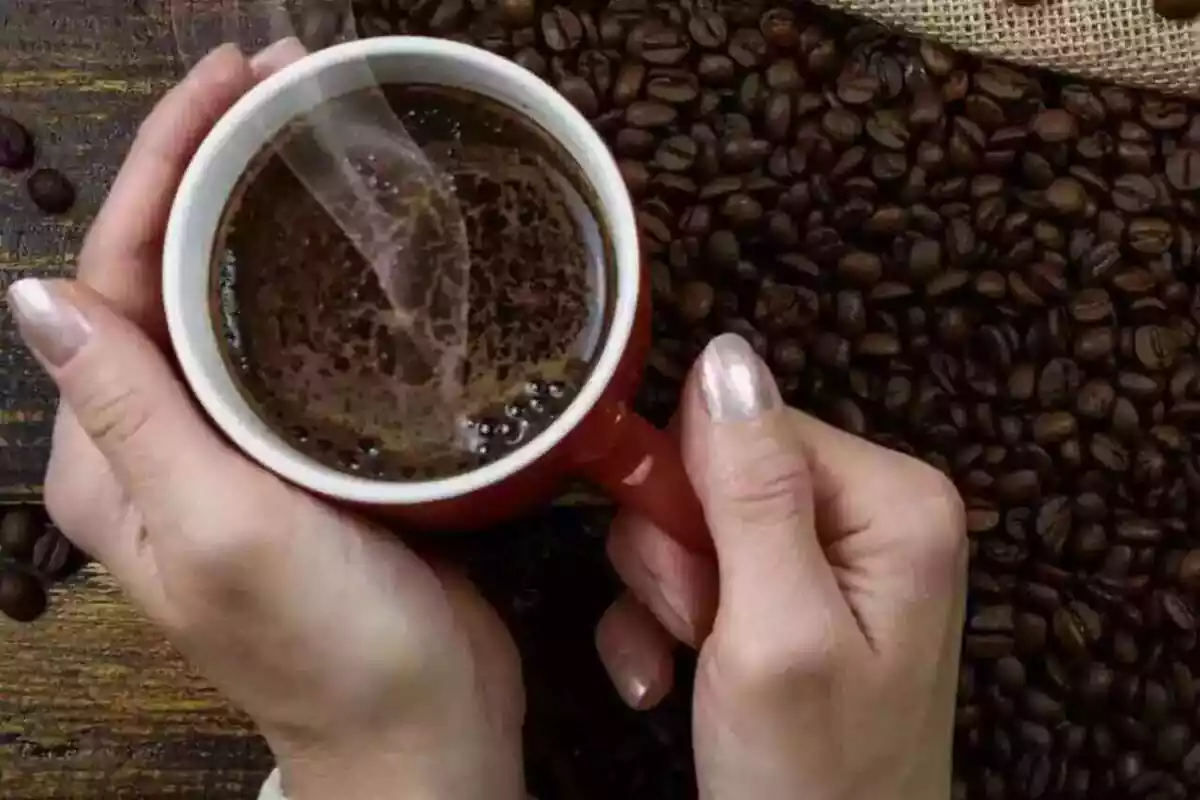 Imatge d'una persona sostenint una tassa de cafe calent