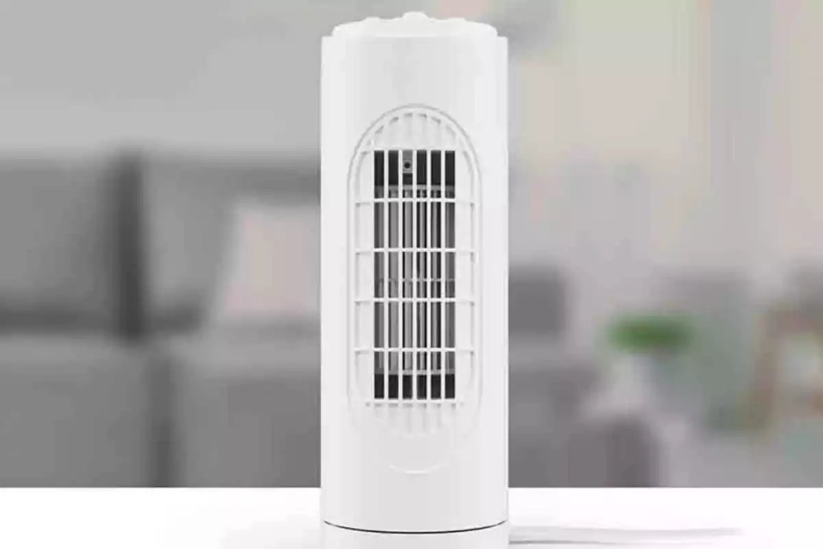 Petit ventilador de torre blanc sobre taula i fons desenfocat