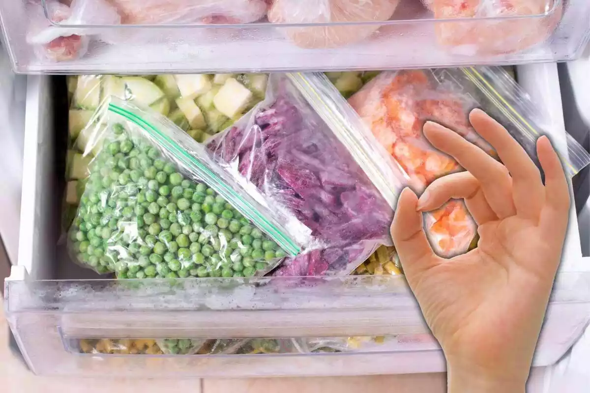 Congelador obert amb diferents tipus de verdures i una mà simulant el gest d'aprovació