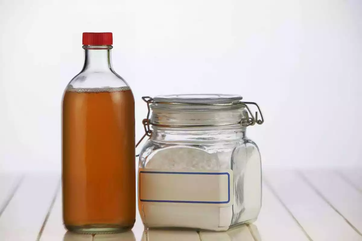 Una ampolla de vinagre al costat d'un recipient amb bicarbonat