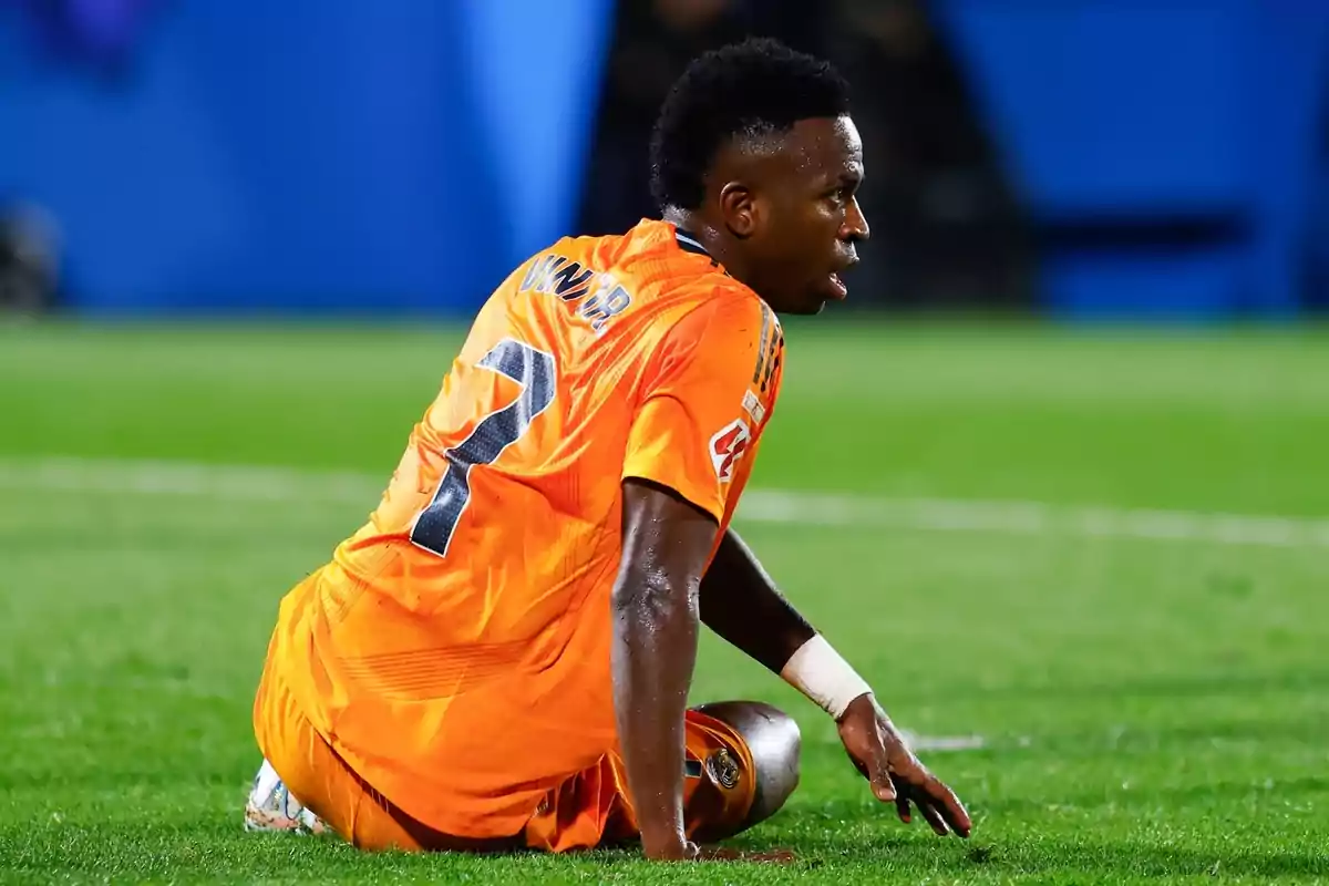 Soccer player in orange uniform sitting on the grass during a match. Soccer player in orange uniform sitting on the grass during a match.