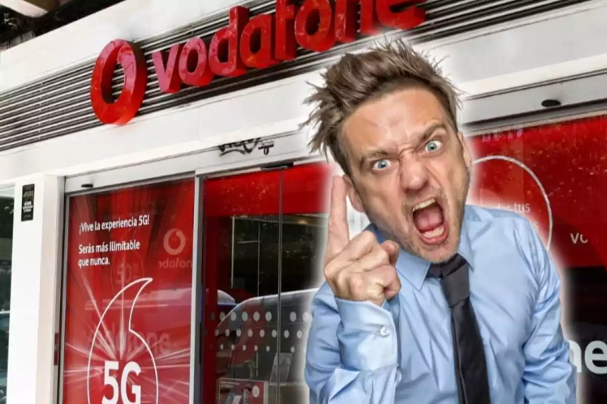 Un home amb expressió d'enuig i assenyalant amb el dit davant una botiga de Vodafone.