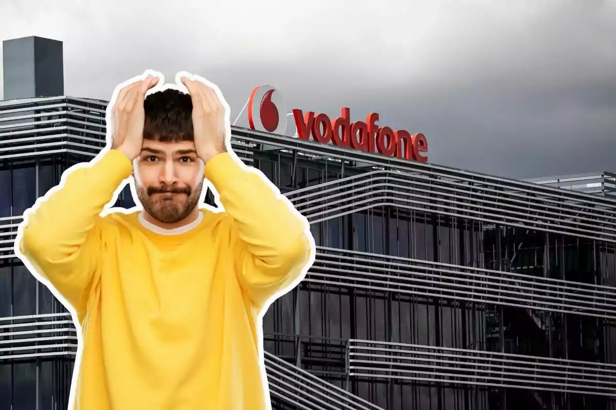 Un home amb suèter groc es mostra preocupat davant d'un edifici d'oficines amb el logotip de Vodafone.