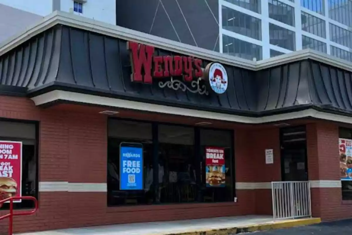 Fachada de un restaurante de comida rápida con letrero rojo y ventanas con carteles promocionales. Fachada de un restaurante de comida rápida con letrero rojo y ventanas con carteles promocionales.