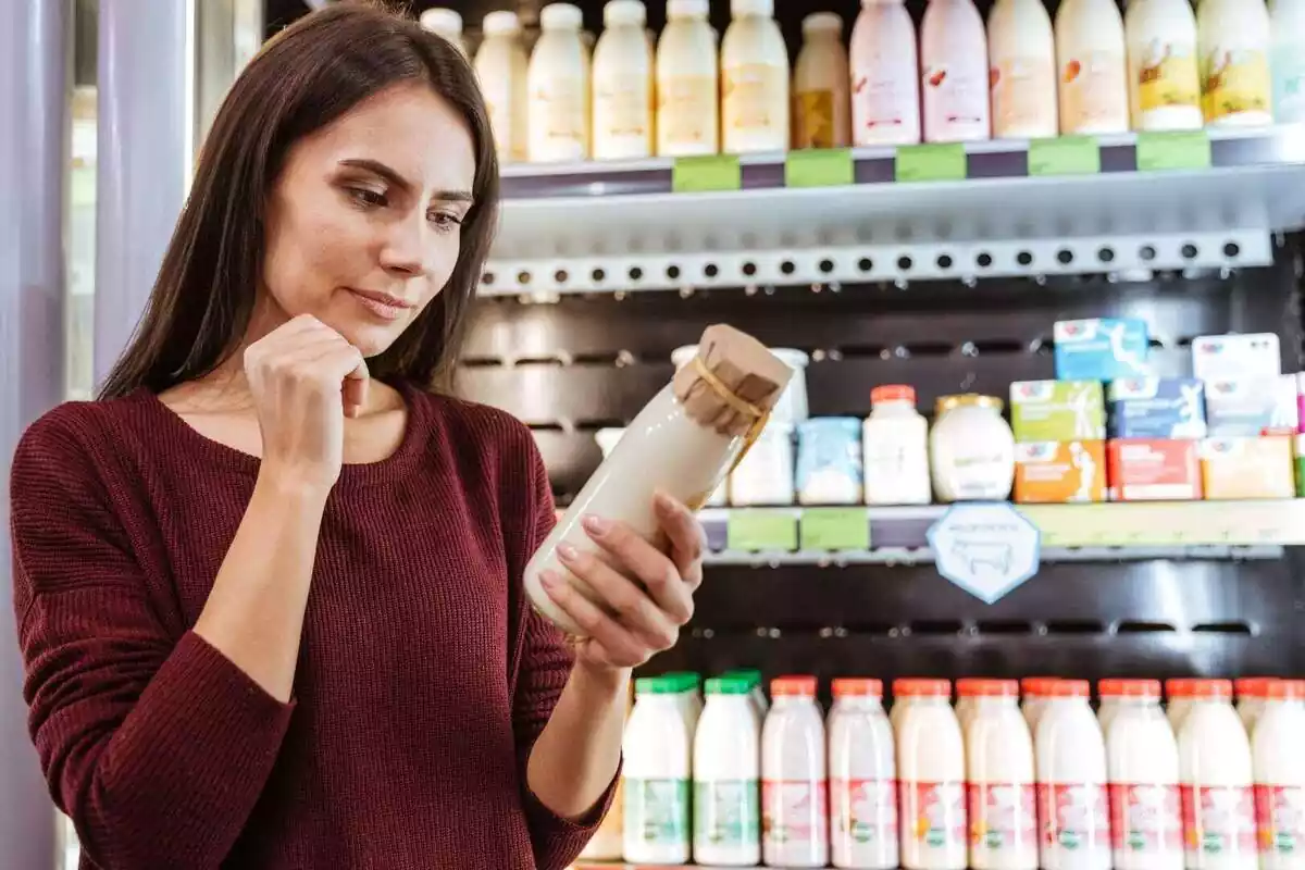 Primer pla d'una dona comprant iogurt líquid a un supermercat