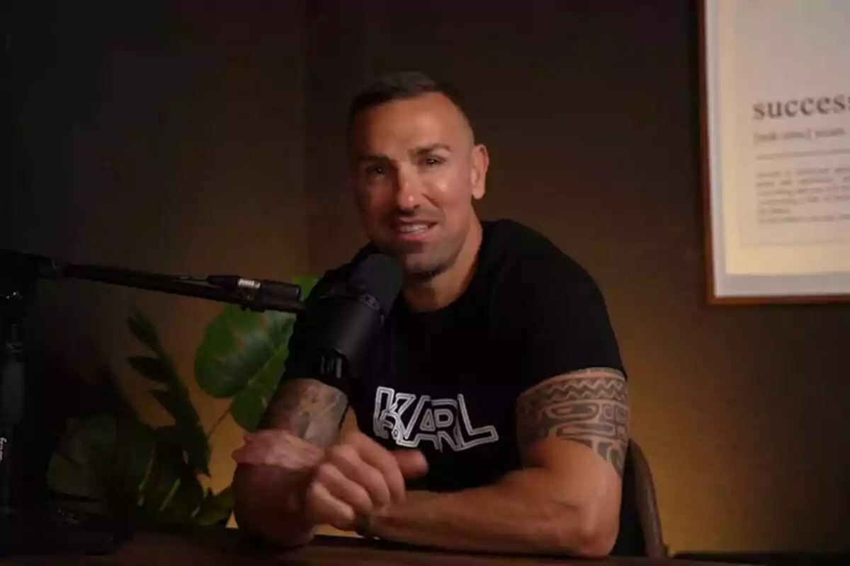 Rafa Mora amb tatuatges als braços parlant davant d'un micròfon en un estudi amb una planta i un quadre a la paret. Captura de YouTube el 24 de juny de 2024 Rafa Mora amb tatuatges als braços parlant davant d'un micròfon en un estudi amb una planta i un quadre a la paret. Captura de YouTube el 24 de juny de 2024