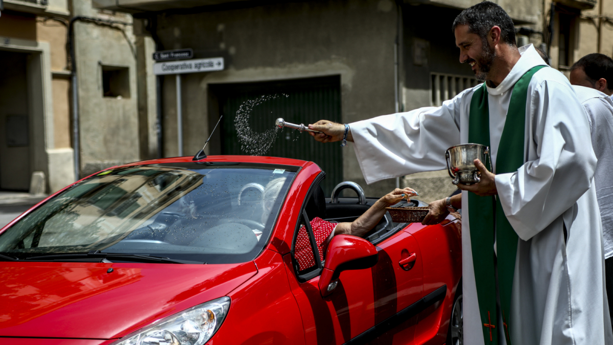 El mossèn Àguila beneeix un vehicle a Valls durant la celebració de Sant Cristòfol, patró dels conductors.