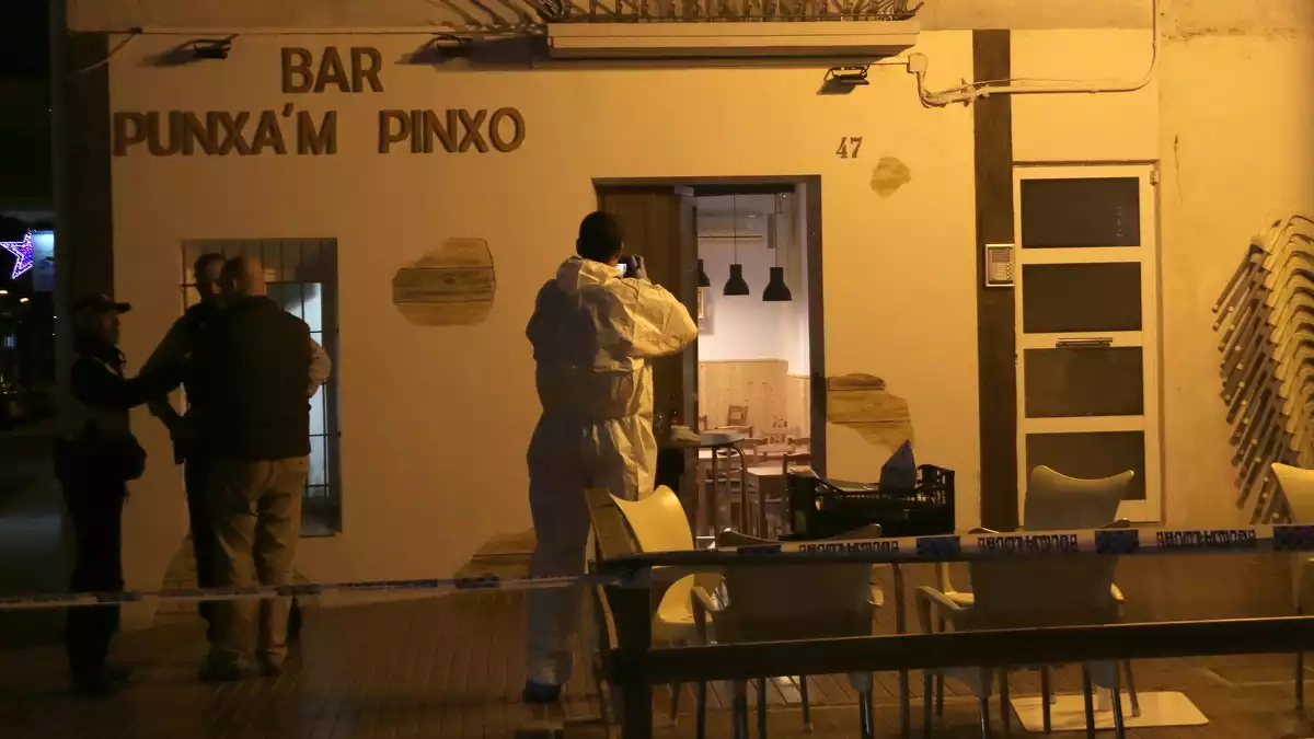 La façana del bar Punxa'm Pinxo de Sant Carles de la Ràpita amb un agent de la policia científica dels Mossos